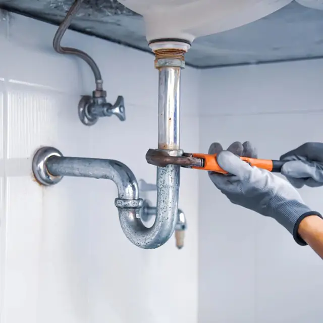 Réparation d'une tuyauterie sous un lavabo à la clé